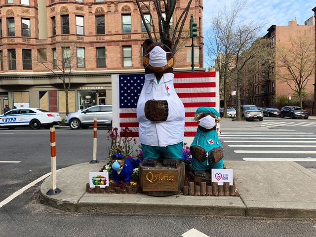 Wooden bears on a traffic median on the Upper West Side wear scrubs and masks